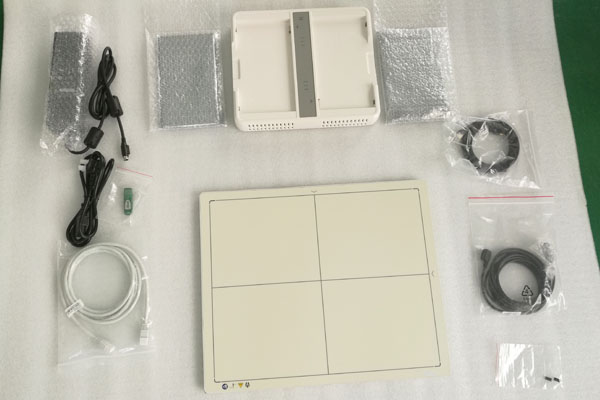 A flat panel detector kit unpacked: panel, power adapters, cables and mounting parts
